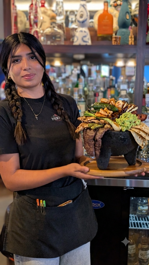 A Fuentes server presenting a sizzling molcajete at the cantina.